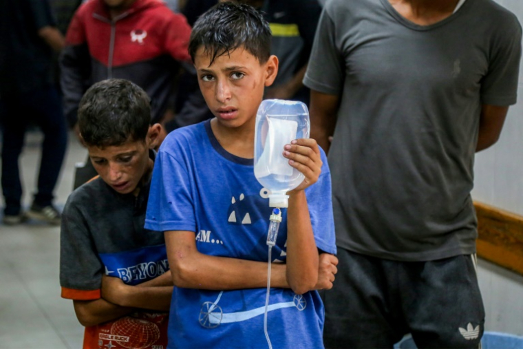 Un jeune palestinien tient une perfusion pour un homme blessé à l'hôpital Nasser, à Khan Younès, dans le sud de la bande de Gaza, le 20 juillet 2025 ( AFP / - )