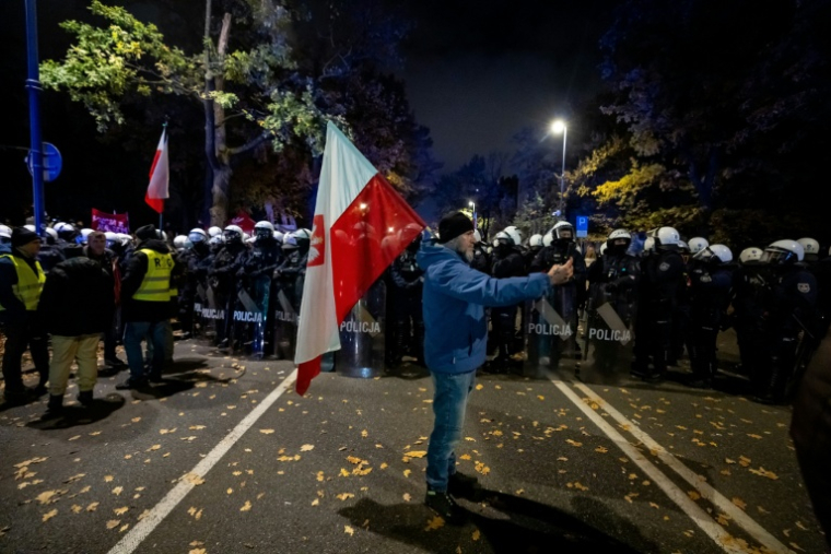 Un manifestant tient un drapeau polonais face à un cordon de policier près de la Cour constitutionnelle, le 30 octobre 2026 à Varsovie ( AFP / Wojtek RADWANSKI )