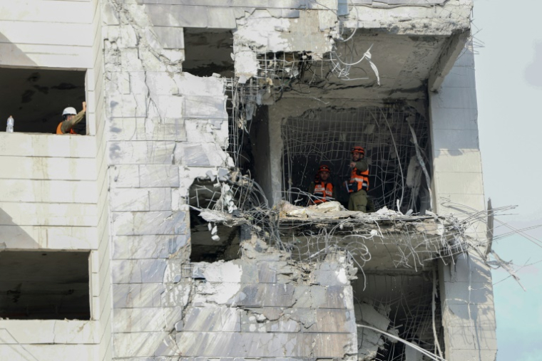 Des secouristes inspectent un bâtiment endommagé à la suite d’une frappe de missile iranien dans la ville israélienne de Petah Tikva, à l’est de Tel-Aviv, le 16 juin 2025 ( AFP / Jack GUEZ )