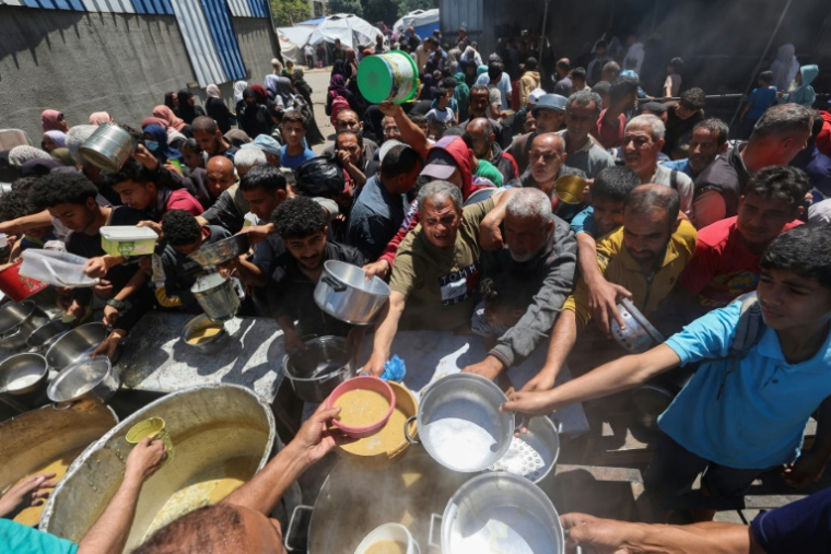 Des Palestiniens font la queue pour un repas chaud dans une cuisine caritative gérée par le Programme alimentaire mondial (PAM) des Nations Unies, au camp de réfugiés de Nuseirat, dans le centre de la bande de Gaza, le 26 avril 2025 ( AFP / Eyad BABA )