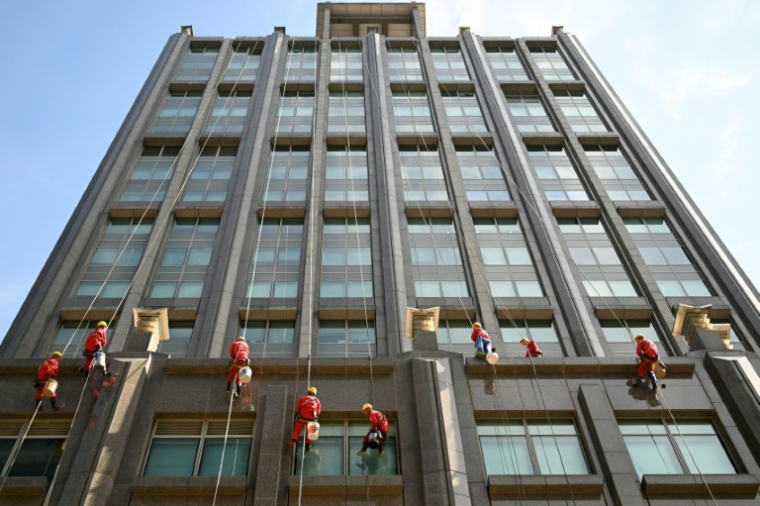 Des laveurs de vitres sur la façade d'un immeuble à Pékin, le 20 octobre 2025 ( AFP / Pedro PARDO )