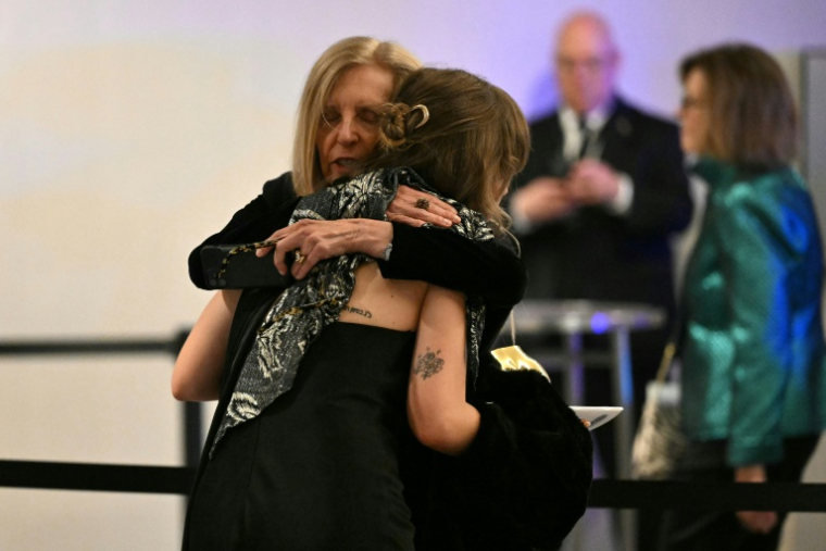 Des invitées du dîner des correspondants de la Maison Blanche s'étreignent après que des détonations ont étét entendues, à l'hôtel Washington Hilton, le 25 avril 2026  ( AFP / Mandel NGAN )