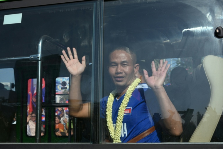 Un soldat cambodgien, capturé par la Thaïlande en juillet, salue la foule depuis un bus après sa libération, alors que le groupe quitte l'ancien aéroport international de Phnom Penh le 31 décembre 2025 ( AFP / TANG CHHIN Sothy )