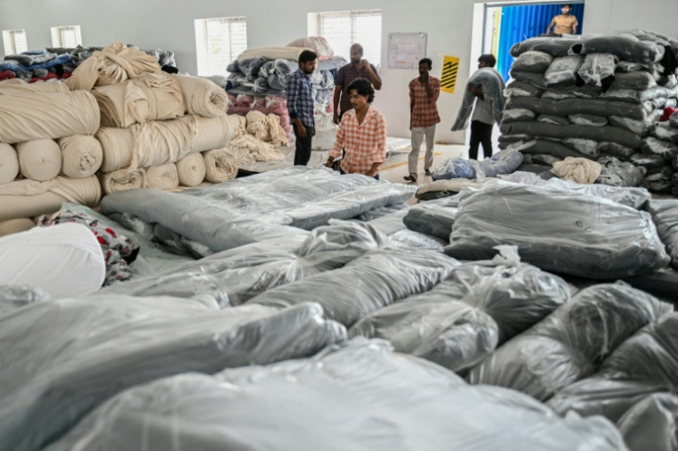 Des ouvriers stockent des tissus utilisés pour fabriquer des t-shirts dans une usine de confection à Tiruppur, dans l'État du Tamil Nadu, dans le sud de l'Inde, le 24 septembre 2025 ( AFP / R. Satish BABU )
