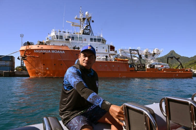 Le biologiste marin Teina Rongo passe en bateau devant le navire de recherche Anuanua Moana, le 12 juin 2025 à Rarotonga, aux îles CooK ( AFP / William WEST )