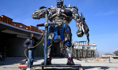 Le sculpteur Ehtisham Jadoon à côté de son Optimus Prime, personnage du film Transformers, fabriqué à partir de ferraille devant son atelier situé à la périphérie d'Islamabad, le 12 février 2026 au Pakistan ( AFP / Farooq NAEEM )