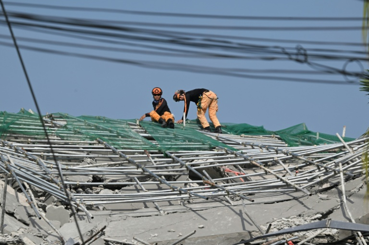 Des pompiers sur le site d'un immeuble effondré lors d'opérations de recherche et de sauvetage à Angeles City, dans la province de Pampanga, au nord de Manille, le 25 mai 2025 aux Philippines ( AFP / Ted ALJIBE )