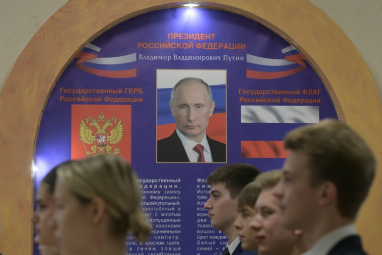 Des élèves chanter l'hymne national russe devant un portrait de Vladimir Poutine à l'ouverture du scrutin dans un bureau de vote installé dans l'enceinte d'un lycée, lors des législatives russes à Donetsk, dans l'est de l'Ukraine sous contrôle russe, le 18 septembre 2026 ( AFP / STRINGER )