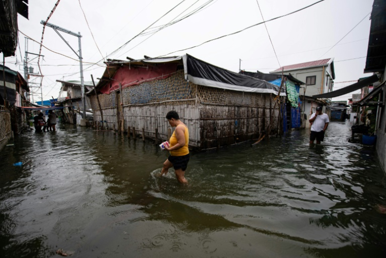 Des habitants dans une rue inondée de l'île de Pugad, dans la province de Bucalan, le 21 août 2025 aux Philippines ( AFP / Ted ALJIBE )