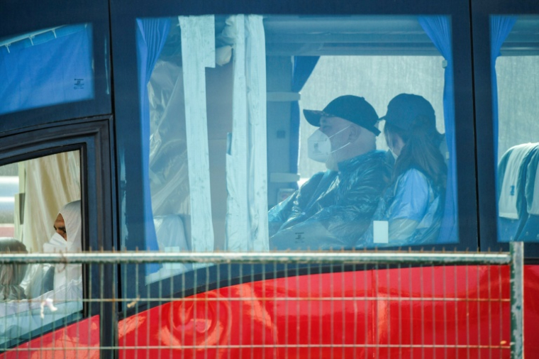 Un passager porte une combinaison de protection et un masque à bord d'un autobus après avoir été évacué du navire de croisière touché par un foyer d'hantavirus, le 10 mai 2026 à Granadilla de Abona, sur l'île espagnole de Tenerife  ( AFP / JORGE GUERRERO )