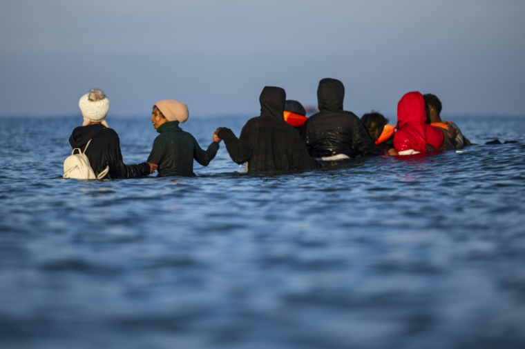 Des migrants avancent dans l'eau pour monter à bord d'un bateau de passeurs et tenter de traverser la Manche, au large de la plage de Gravelines, le 27 septembre 2025 dans le Nord ( AFP / Sameer Al-DOUMY )