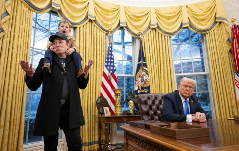 Elon Musk,, son fils sur les épaules à côté du président américain Donald Trump dans le Bureau ovale de la Maison Blanche, le 11 février 2025 à Washington ( AFP / Jim WATSON )
