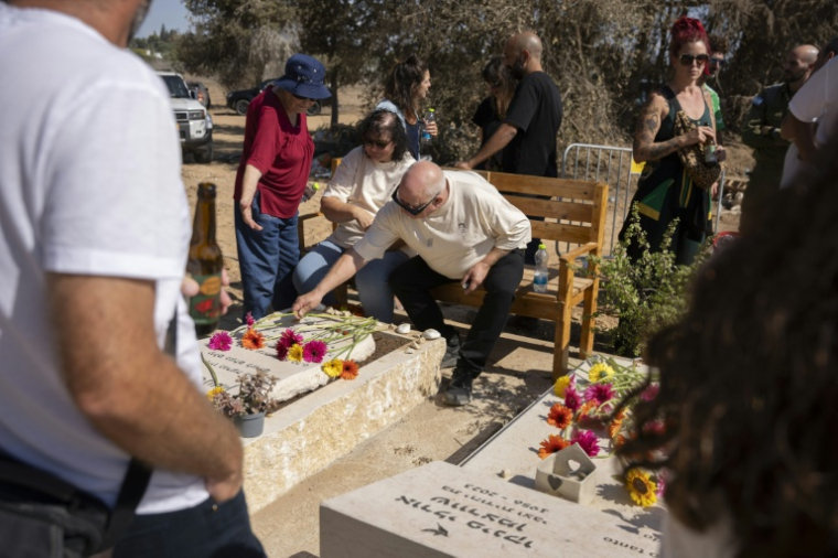 Des habitants du kibboutz Kfar Aza fleurissent les tombes de victimes de l'attaque du 7 octobre 2023, le 16 octobre 2023 à Kfar Aza ( AFP / Maya Levin )
