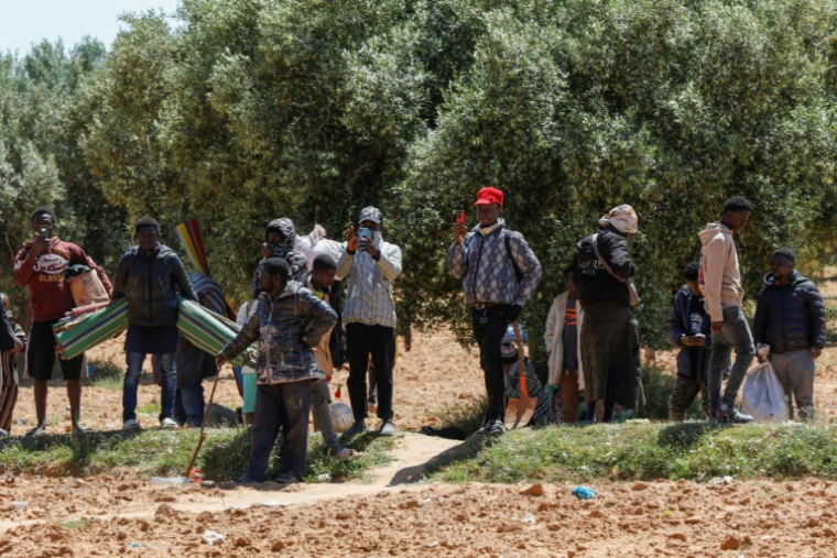 Des migrants d'Afrique subsaharienne quittent avec leurs biens le camp d'al-Amra démantelé par les autorités, à la périphérie de la ville de Sfax, le 24 avril 2025 en Tunisie ( AFP / Mohamed KHALIL )