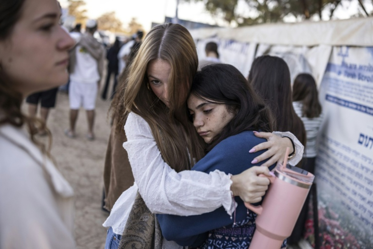 Des jeunes femmes s'étreignent devant le mémorial dédié aux victimes des attaques du Hamas de 2023, sur le site du festival Nova à Réïm, dans le sud d'Israël, le 7 octobre 2026 ( AFP / JOHN WESSELS )