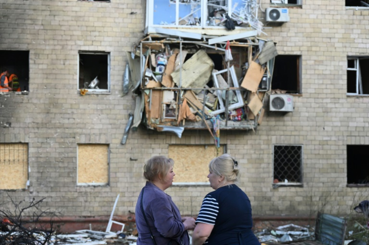 Des habitantes devant un immeuble endommagé par une frappe russe à Kharkiv, le 11 juin 2025 en Ukraine ( AFP / SERGEY BOBOK )