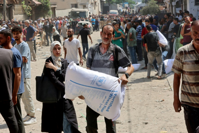 Un Palestinien porte un sac de farine près d'un entrepôt du Programme alimentaire mondial (PAM) dans la ville de Gaza, le 12 juillet 2025 ( AFP / Omar AL-QATTAA )