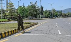 Un agent de sécurité place du fil barbelé sur une route menant à l'hôtel Serena à Islamabad (Pakistan), le 19 avril 2026 ( AFP / Aamir QURESHI )