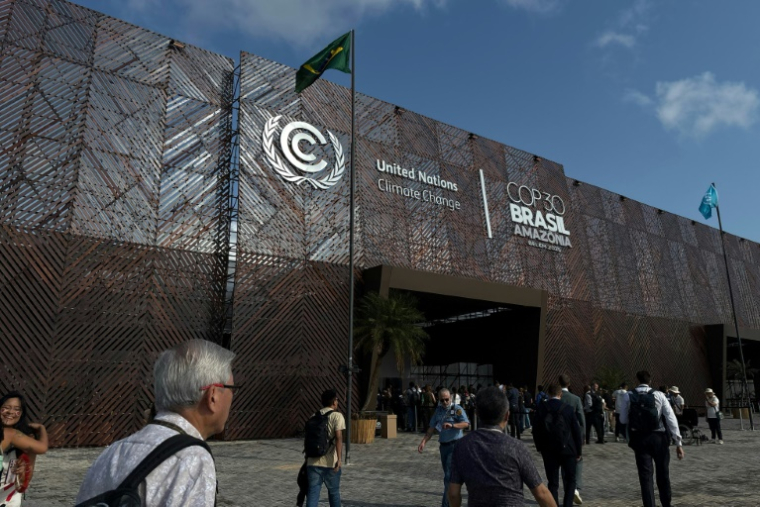 Attendees walk in front of the main entrance to the COP30 UN Climate Change Conference in Belem, Para State, Brazil on November 10, 2025. The COP30 runs from November 10 to 21, and the 50,000 participants will feel the heavy, humid air of the Amazon rainforest, and face the daunting task of keeping global climate cooperation from collapsing.. ( AFP / MAURO PIMENTEL )