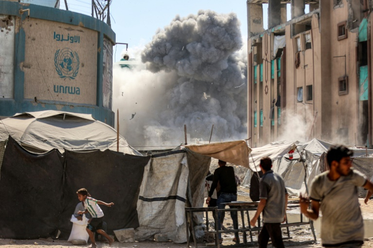 Des gens courent alors que de la fumée s'élève au-dessus d'un bâtiment dans la ville de Gaza, le 14 septembre 2025 ( AFP / Omar AL-QATTAA )