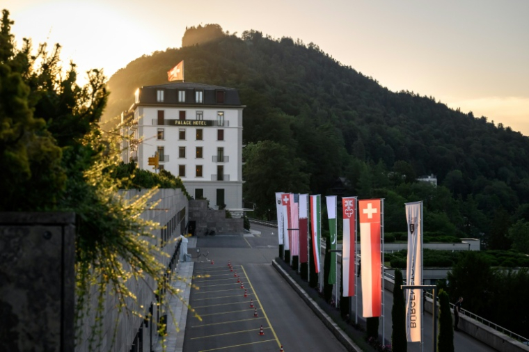 Les drapeaux de l'Iran, des Etats-Unis, du Pakistan, du Qatar et de la Suisse flottent devant le complexe hôtelier de luxe du Bürgenstock, le 21 juin 2026 en Suisse ( AFP / Fabrice COFFRINI )