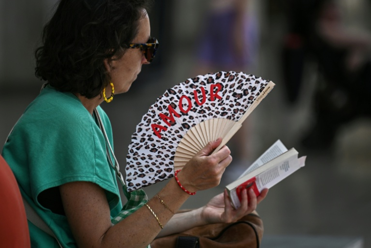 Une voyageuse se rafraîchit un éventail en attendant son train à la gare Saint-Jean, à Bordeaux, alors quune nouvelle vague de chaleur en France  entraîn des perturbations du trafic ferroviaire, le 9 juillet 2026 ( AFP / Christophe ARCHAMBAULT )