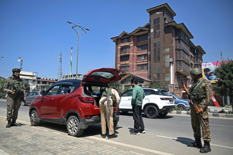 Des paramilitaires indiens montent la garde pendant qu'un policier inspecte un véhicule dans une rue de Srinagar, le 30 avril 2025 au Cachemire indien ( AFP / Tauseef MUSTAFA )