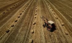 Vue aérienne d'un tracteur dans un champ moissonné, parsemé de bottes de paille, après une récolte de céréales précoce en raison d'une vague de chaleur estivale, près de Ségalas, le 8 juillet 2026 dans le Lot-et-Garonne ( AFP / Philippe LOPEZ )