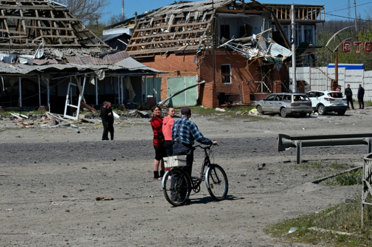 Des habitants de Merefa, dans l'est de l'Ukraine, passent près de bâtiments et de voitures endommagés par une frappe de missile russe, le 4 mai 2026 ( AFP / SERGEY BOBOK )