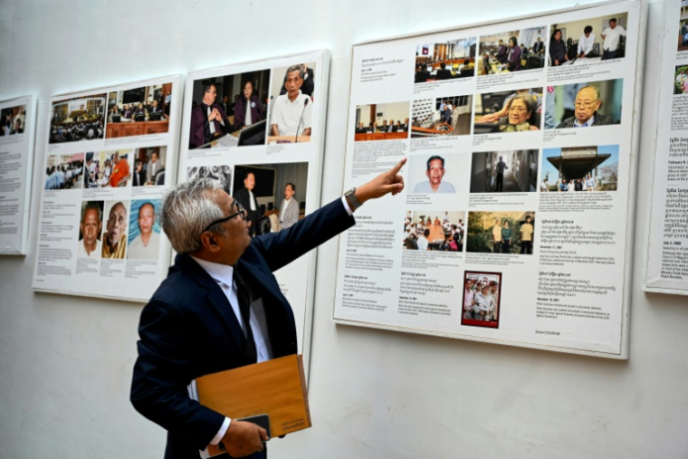 Le directeur du Centre de documentation du Cambodge (DC-CAM), Youk Chhang, montre des photos d'anciens dirigeants Khmer Rouges sur le mur de son bureau à Phnom Penh, le 20 mars 2025 ( AFP / TANG CHHIN Sothy )