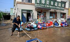 Un habitant du village de Taishitun, dans le district de Miyun à Pékin, évacue la boue apportée par les pluies torrentielles le 28 juillet 2025 ( AFP / Jade GAO )