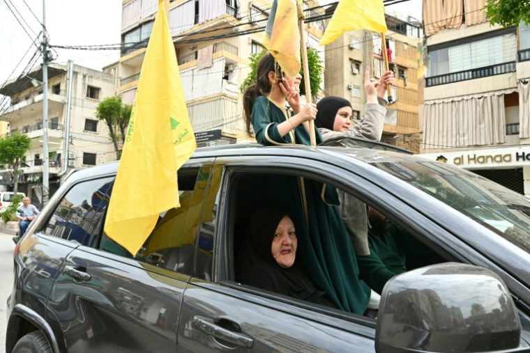 Des enfants tiennent des drapeaux du Hezbollah tandis que des habitants déplacés retournent dans leur quartier de la banlieue sud de Beyrouth après l'entrée en vigueur d'un cessez-le-feu de 10 jours avec Israël, le 17 avril 2026 au Liban ( AFP / FADEL itani )