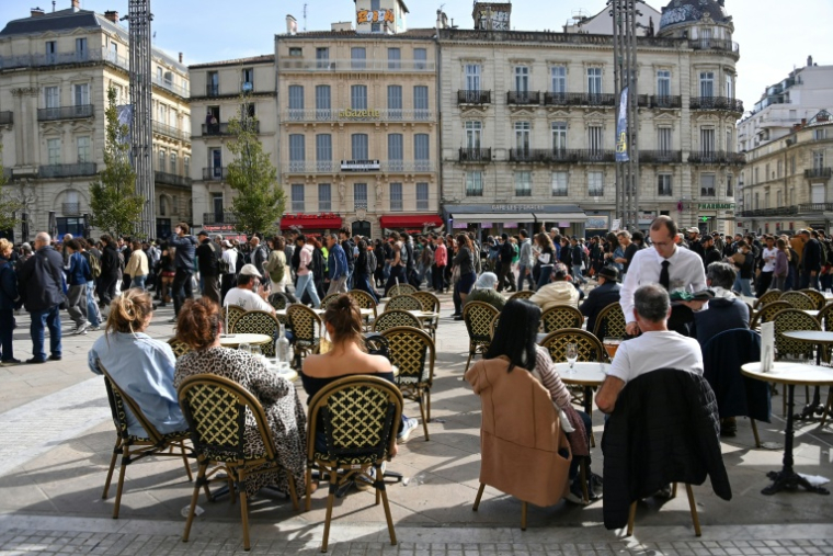 Des clients en terrasse d'un café regardent passer des manifestants, le 24 octobre 2026 à Montpellier  ( AFP / Sylvain THOMAS )