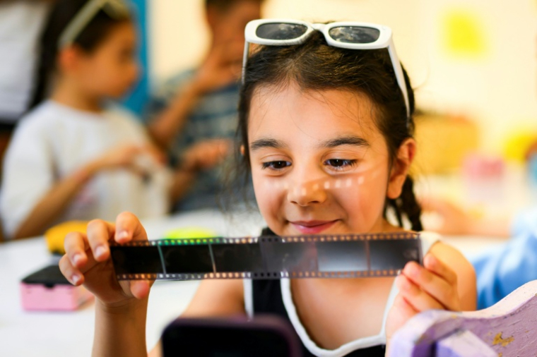 Zeynep, 8 ans, observe une pellicule photographique lors d'un atelier organisé dans le cadre du projet "Fotohane Darkroom" à Mardin, dans le sud-est de la Turquie, le 13 juin 2026 ( AFP / Yasin AKGUL )