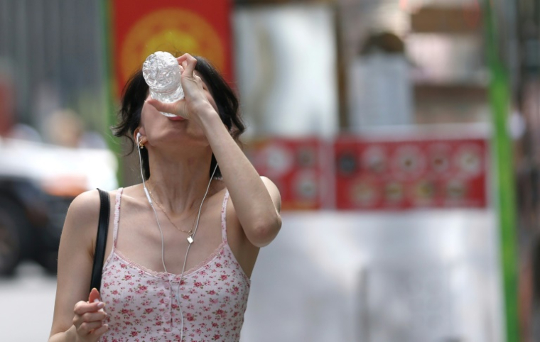 Une passante boit de l'eau alors qu'une alerte à la chaleur extrême a été émise pour la région de New York, le 23 juin 2025 ( AFP / TIMOTHY A. CLARY )