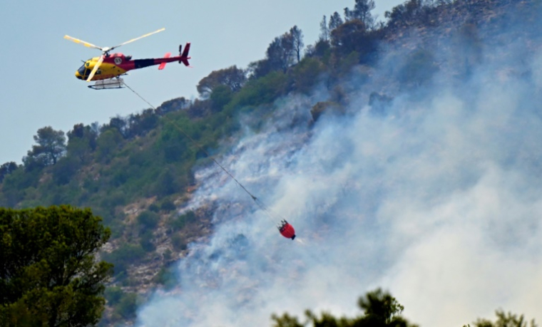 Un hélicoptère des pompiers largue une charge d'eau sur un incendie de forêt près de Tarragone, le 8 juillet 2025 en Espagne ( AFP / JOSE JORDAN )
