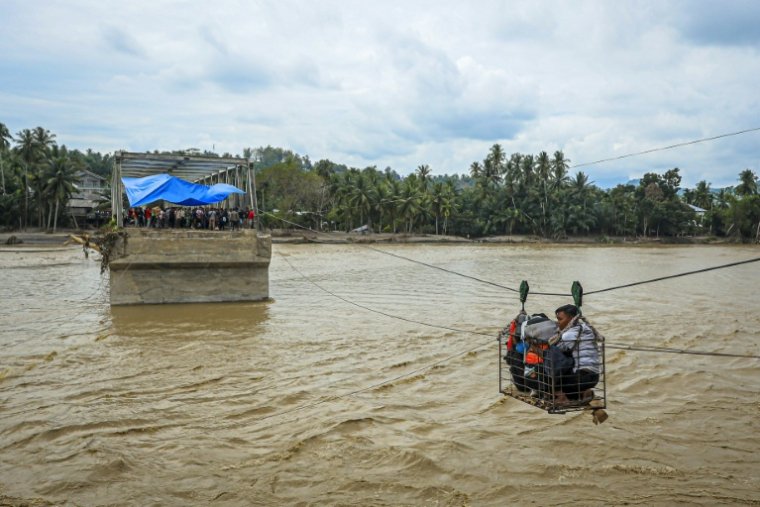Des villageois utilisent une cabine sur câble pour traverser une rivière après la destruction d'un pont à Bireuen, en Indonésie, le 2 décembre 2025 ( AFP / AMANDA JUFRIAN )