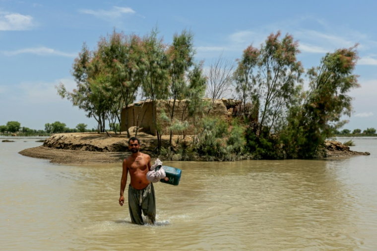 Un homme marche dans l'eau dans un village inondé de la povince pakistanaise du Pendjab, le 16 juillet 2025 ( AFP / Shahid Saeed MIRZA )