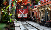 Un train passe au ras des cafés et des habitations dans la célèbre et touristique "rue du train" à Hanoi, le 18 août 2025  ( AFP / Nhac NGUYEN )