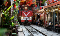 Un train passe au ras des cafés et des habitations dans la célèbre et touristique "rue du train" à Hanoi, le 18 août 2025  ( AFP / Nhac NGUYEN )
