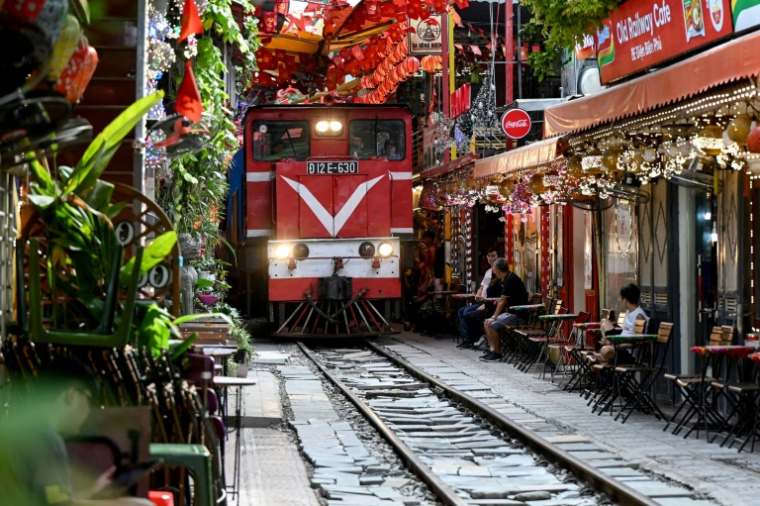 Un train passe au ras des cafés et des habitations dans la célèbre et touristique "rue du train" à Hanoi, le 18 août 2025 ( AFP / Nhac NGUYEN )
