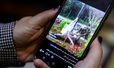 Une femme regarde sur son téléphone, le 20 avril 2026 à Beyrouth, une image semblant montrer un soldat israélien en train de frapper une statue de Jésus dans le sud du Liban ( AFP / Anwar AMRO )