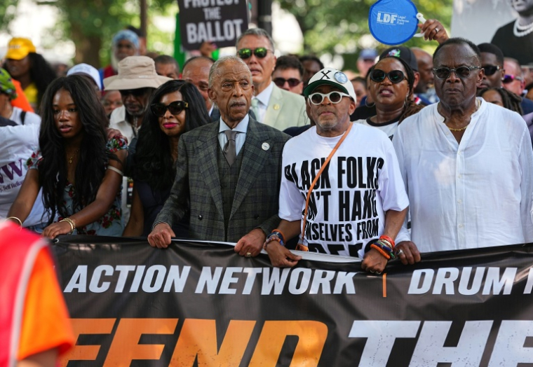 Le révérend Al Sharpton, en costume gris, aux côtés du réalisateur Spike Lee et de membres de la famille de Martin Luther King Jr, défilent à Washington pour le 63e anniversaire de la "Marche sur Washington" pour les droits civiques, le 28 août 2026 ( AFP / Aaron Schwartz )