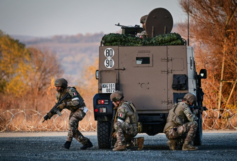 Des militaires français prennent position derrière un véhicule blindé lors de l'exercice militaire "Dacian Fall" de l'Otan au centre logistique de Cartisoara, le 2 novembre 2025 en Roumanie ( AFP / Daniel MIHAILESCU )