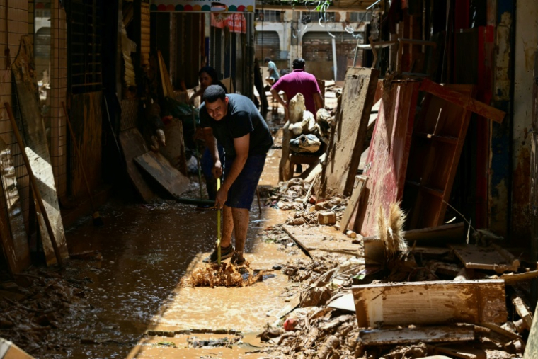 Un homme nettoie une rue boueuse dans le quartier commerçant d'Uba, dans l'État du Minas Gerais, au Brésil, le 25 février 2026 ( AFP / Pablo PORCIUNCULA )