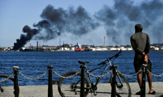 Un homme fixe du regard la fumée noire qui s'échappe d'un incendie à la raffinerie de pétrole Nico Lopes à La Havane, le 13 février 2026 ( AFP / YAMIL LAGE )