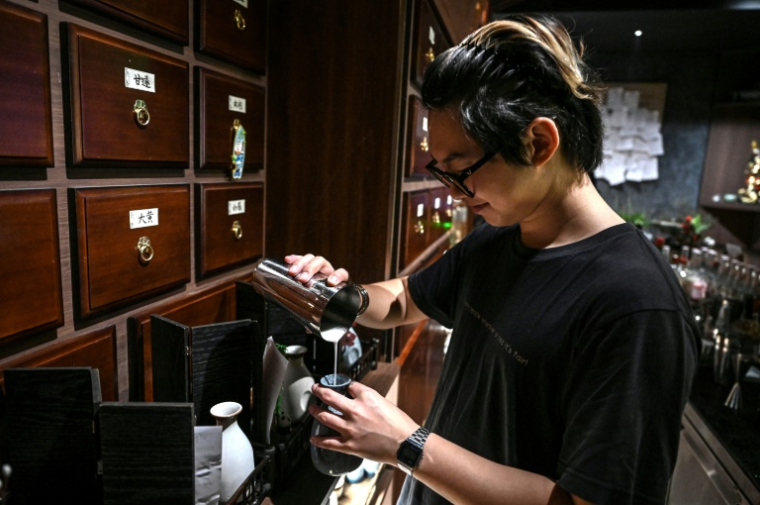 Un barman prépare des cocktails inspirés  de la médecine traditionnelle chinoise dans un bar à Shanghai, le 11 février 2026 en Chine ( AFP / Jade GAO )
