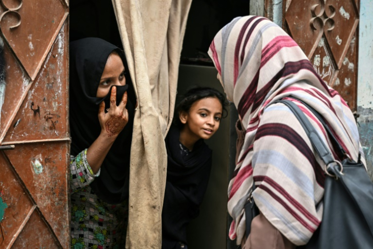 Une agente de santé parle à une femme et sa fille, lors d'une campagne de vaccination porte-à-porte contre le virus du papillome humain (VPH) responsable du cancer du col de l'utérus, le 24 septembre 2025 à Karachi, au Pakistan ( AFP / Rizwan TABASSUM )