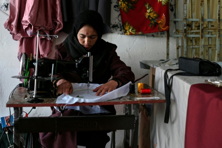 La couturière Rahima Alavi brode à la machine à coudre une écharpe dans sa boutique à Bamiyan, le 26 janvier 2026 en Afghanistan ( AFP / Wakil KOHSAR )