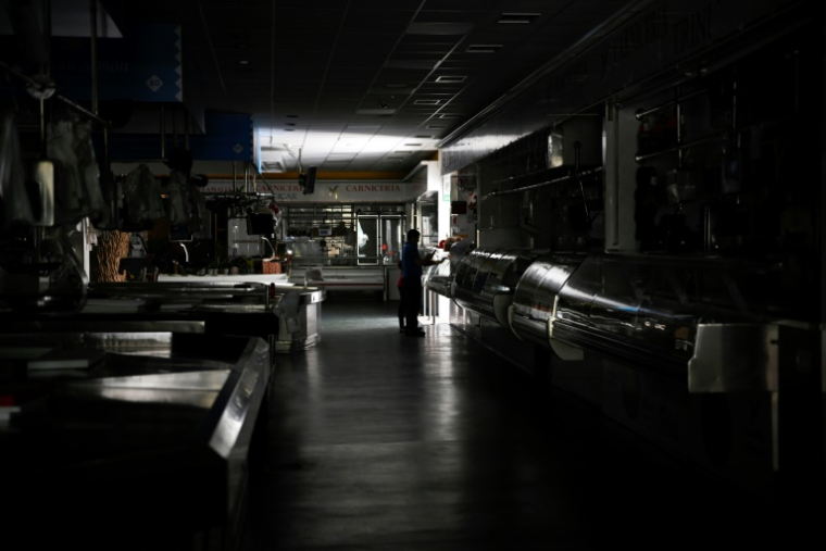 Un homme et un enfant dans un marché couvert plongé dans le noir lors de la panne électrique massive du 28 avril 2025, à Vigo, dans le nord-ouest de l'Espagne ( AFP / MIGUEL RIOPA )